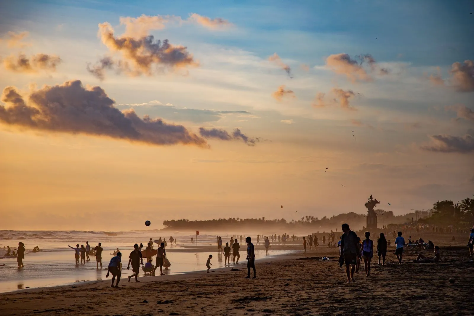 Surfers and evening crowds on the black sand at Canggu